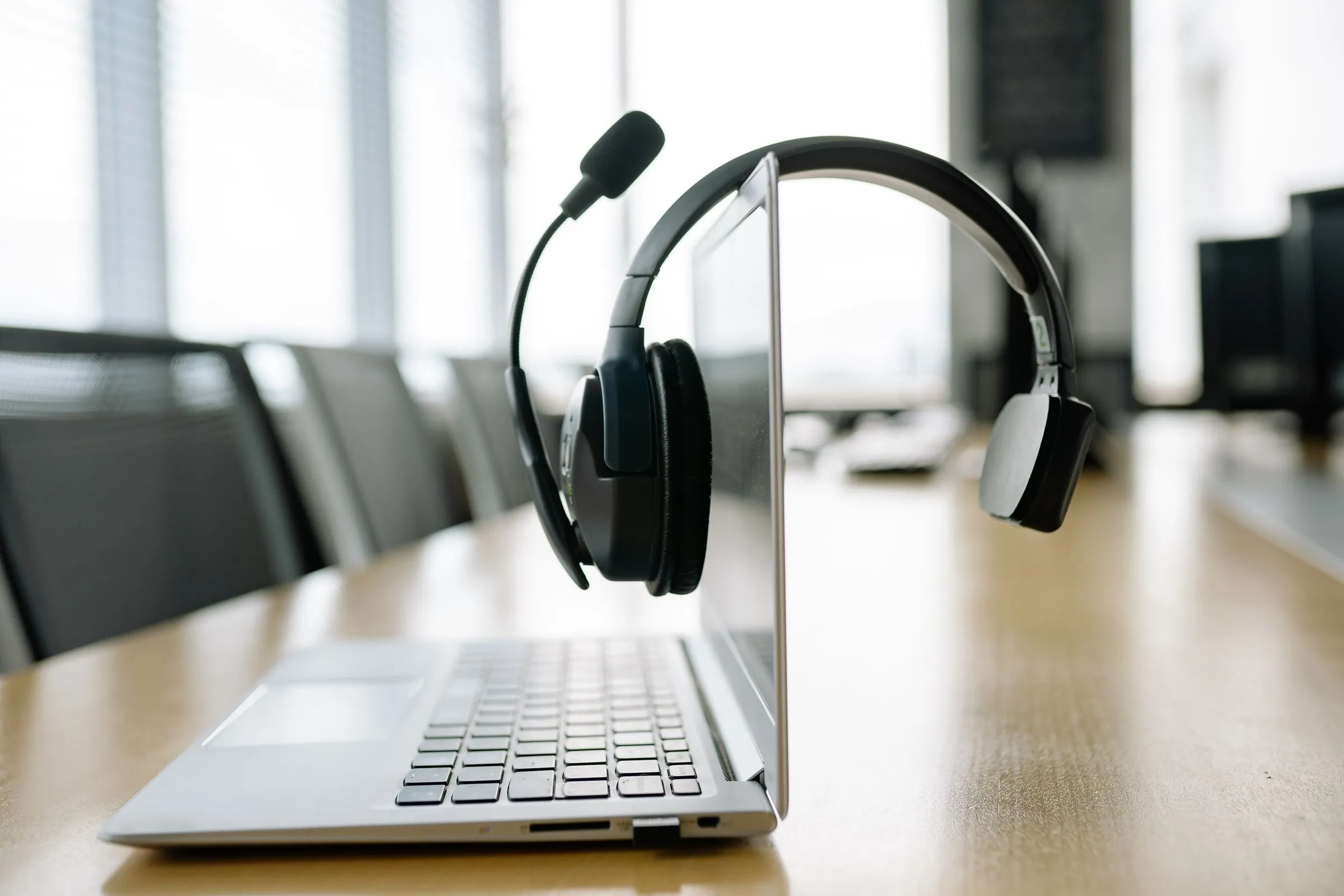 A help desk headset hung over an open laptop